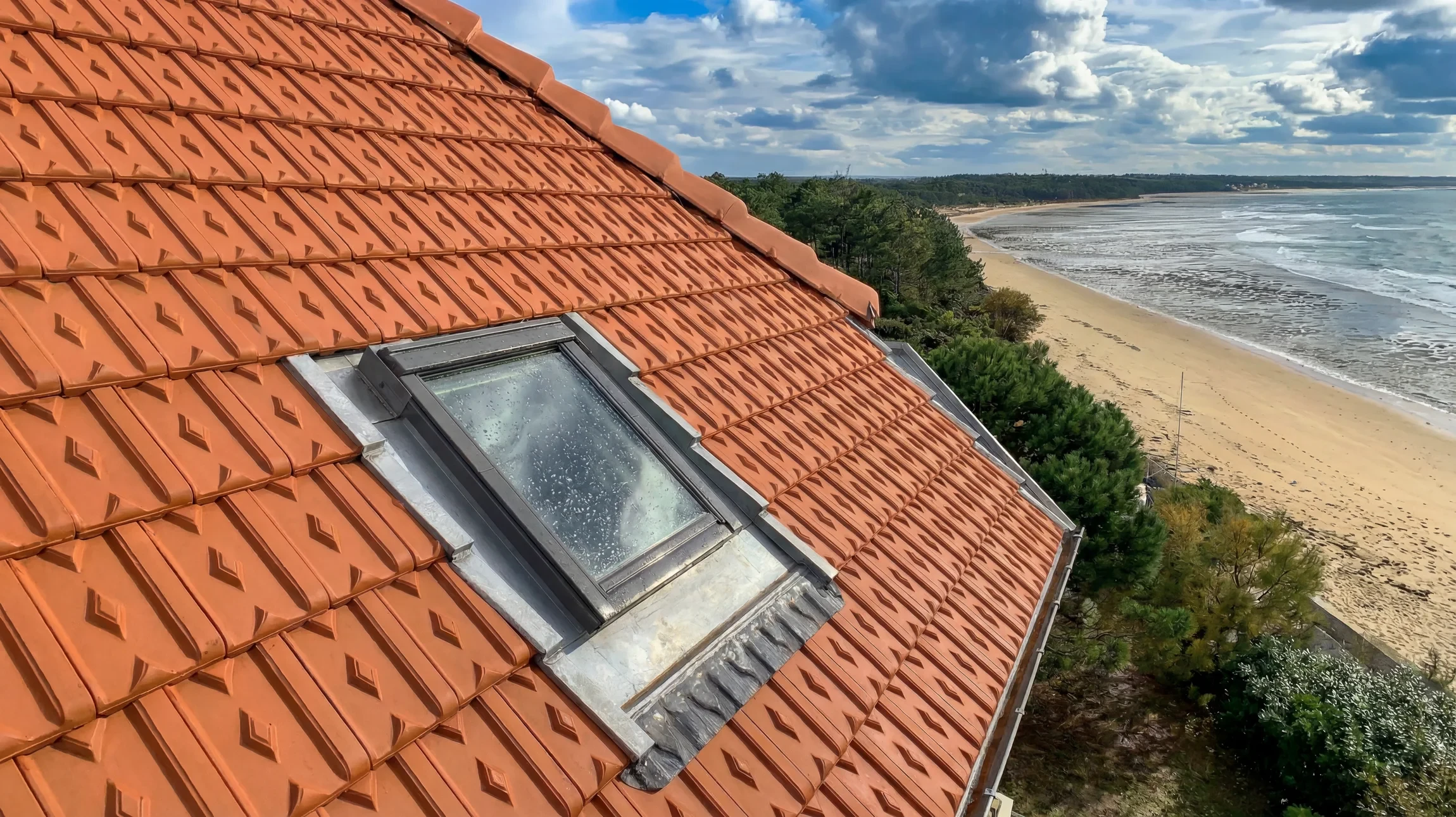 Velux fraîchement installé sur une toiture en tuiles avec vue sur la plage